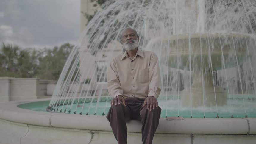 A man sits on the edge of a fountain