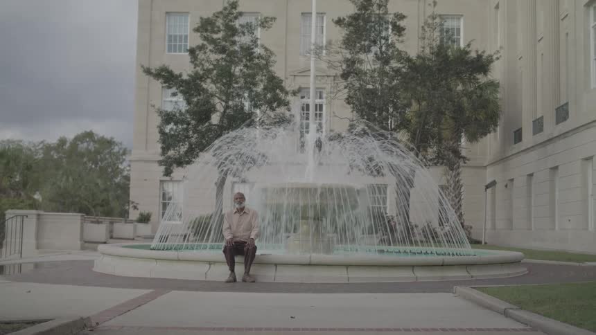 A man sits on the edge of a fountain