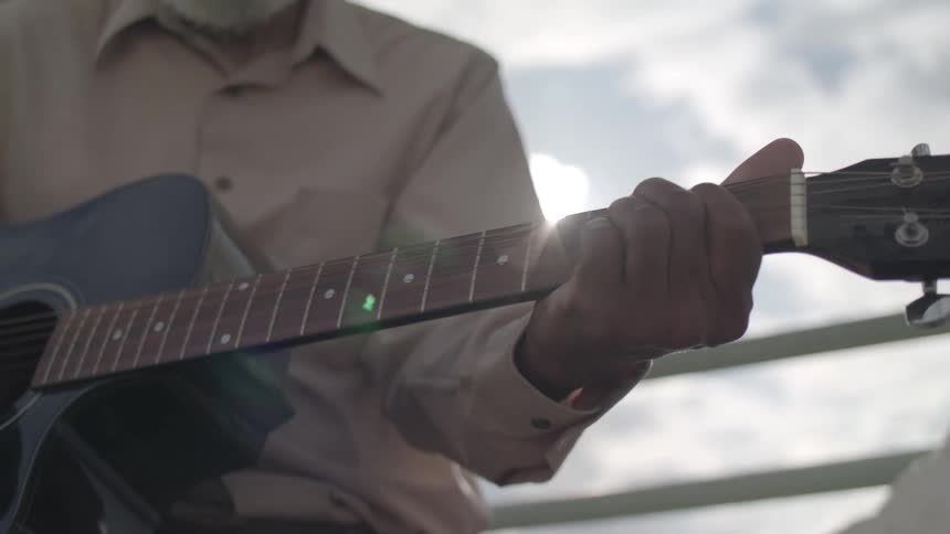 A man is playing the guitar outside