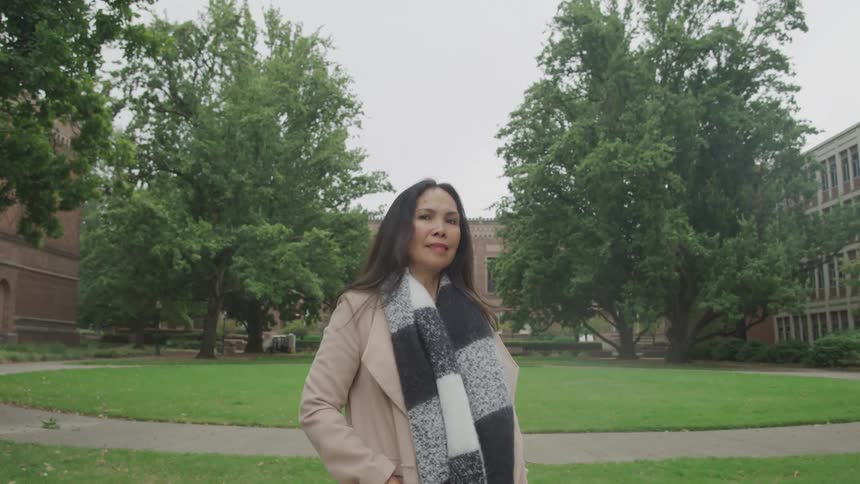 Woman in scarf on a campus with trees and buildings around