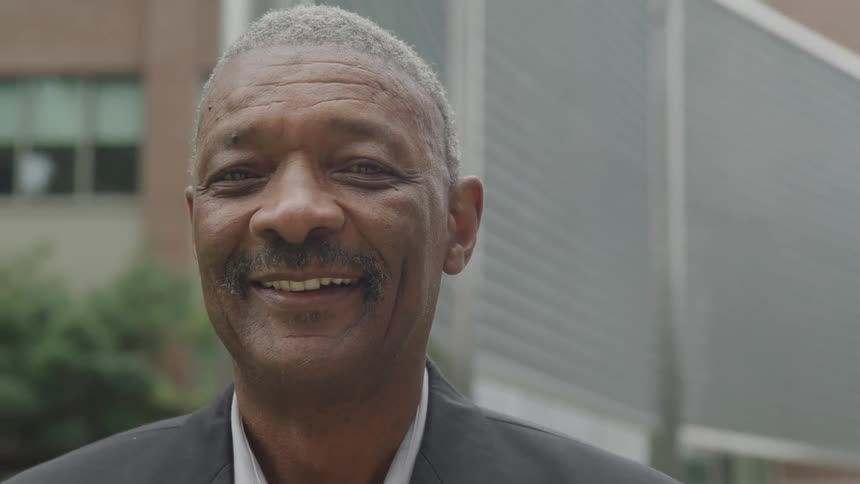 Close up portrait of a middle aged black man smiling while standing outdoors during daytime