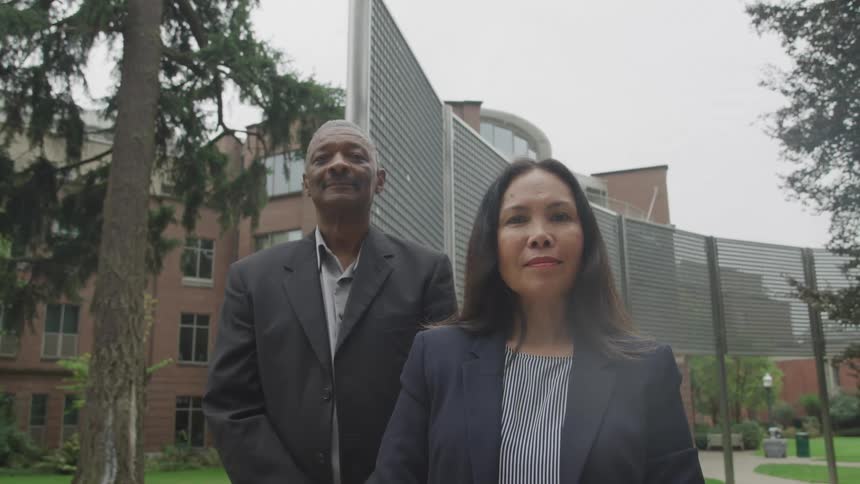 A man and woman are smiling outside the building