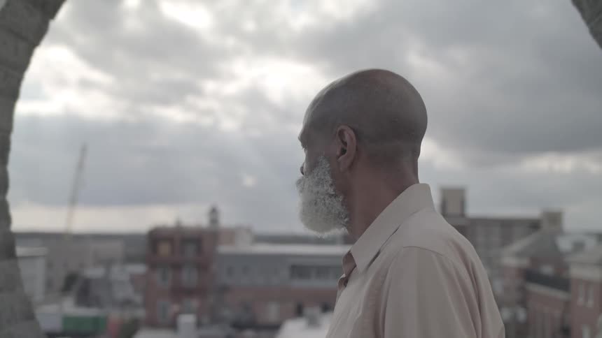 White bearded man looking at city skyline
