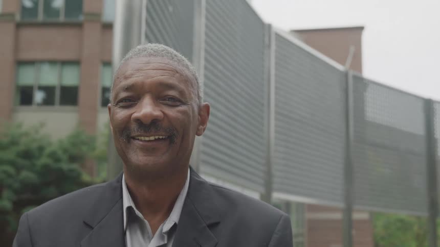 A man smiles in front of a building