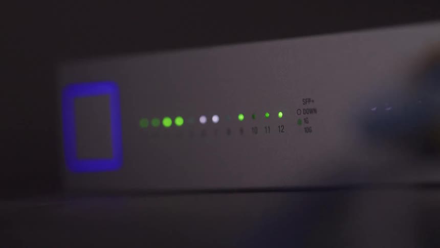 A white modem or router displays several green and white indicator lights with a blue square light on the left