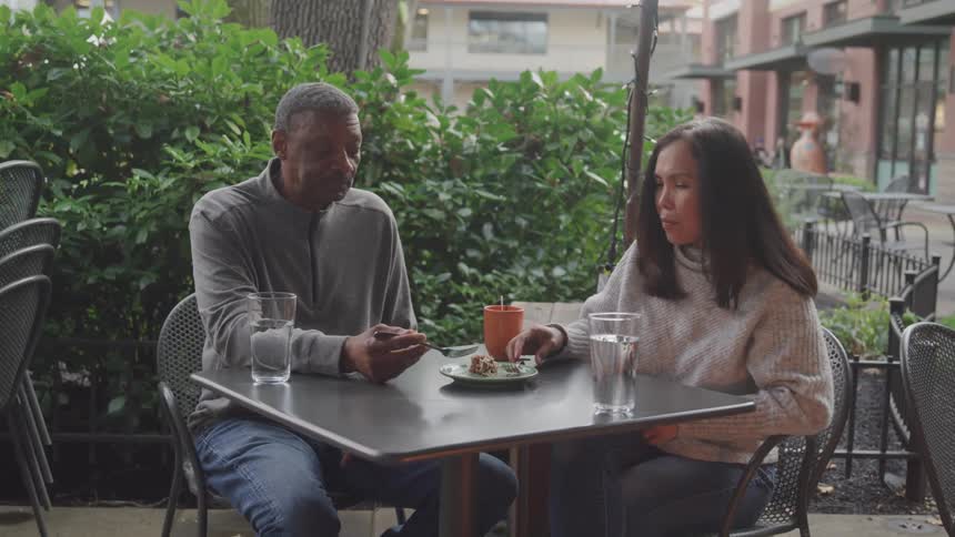 A man and woman are eating outdoors at the restaurant