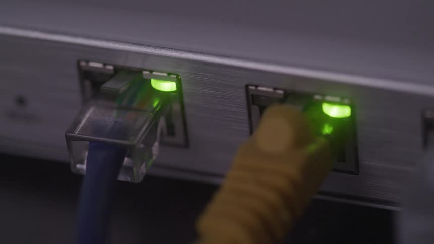 Two different colored cables connected to a modem with a blinking green light