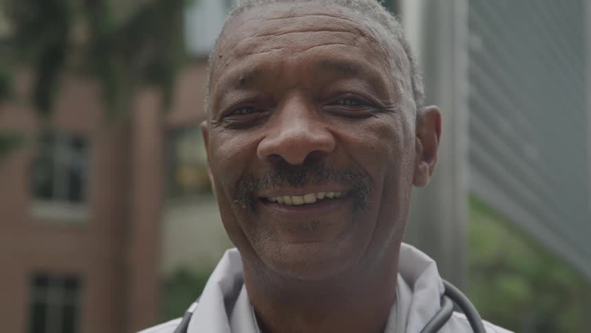 An older man smiles at the camera