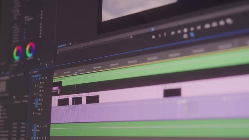 A video editing interface displays multiple timeline tracks color correction wheels and clip previews arranged across a dark workspace