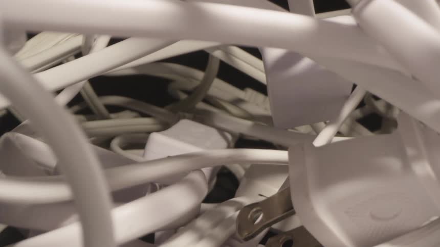 A pile of white tangled cables rests on a dark surface