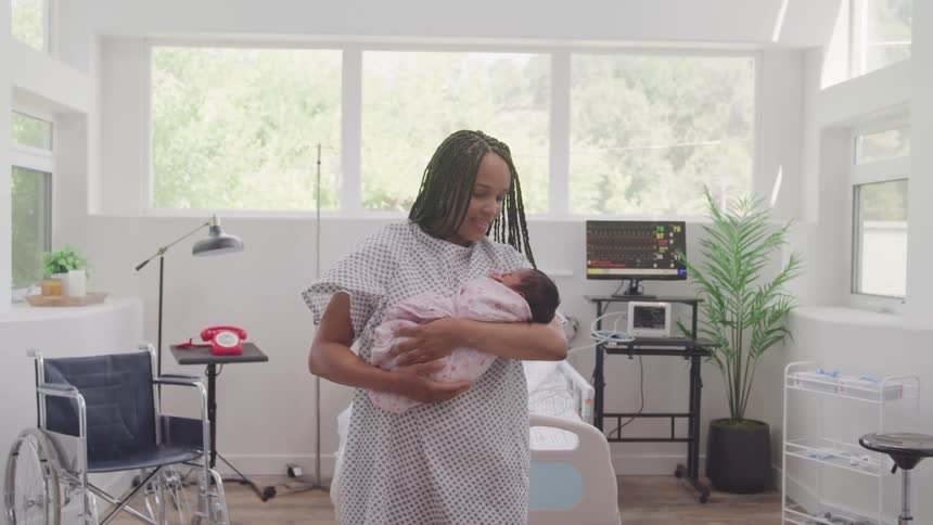 Woman holding her newborn baby in a hospital room