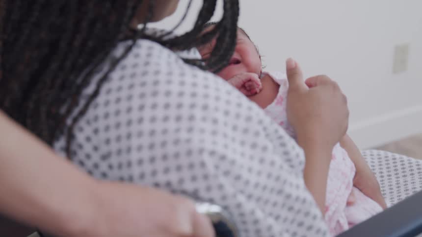Newborn baby crying in mothers arms