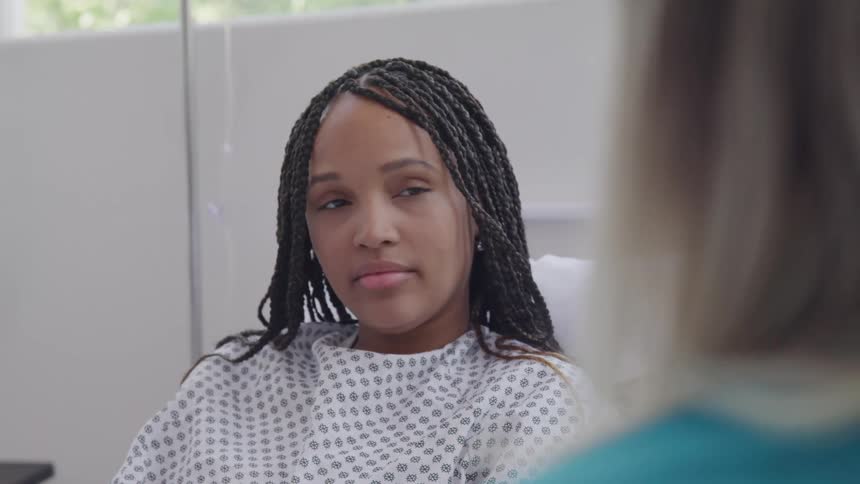 Woman lying in a hospital bed accompanied by another person