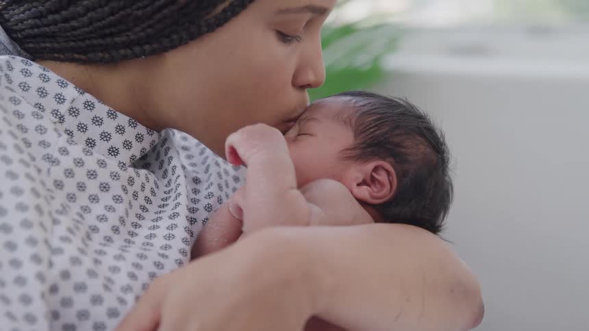 Mother giving a kiss to her newborn baby