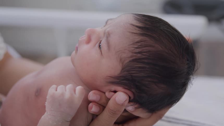 A newborn baby in a womans arms