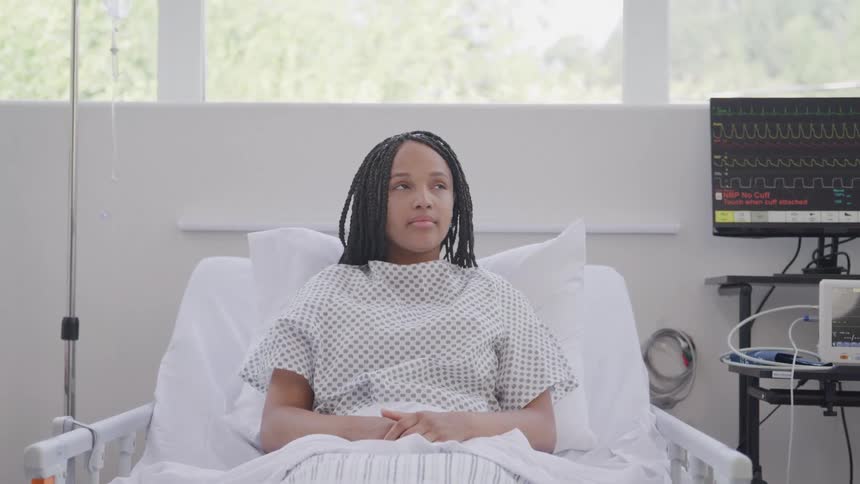 A woman lies calmly in a hospital bed with her eyes closed