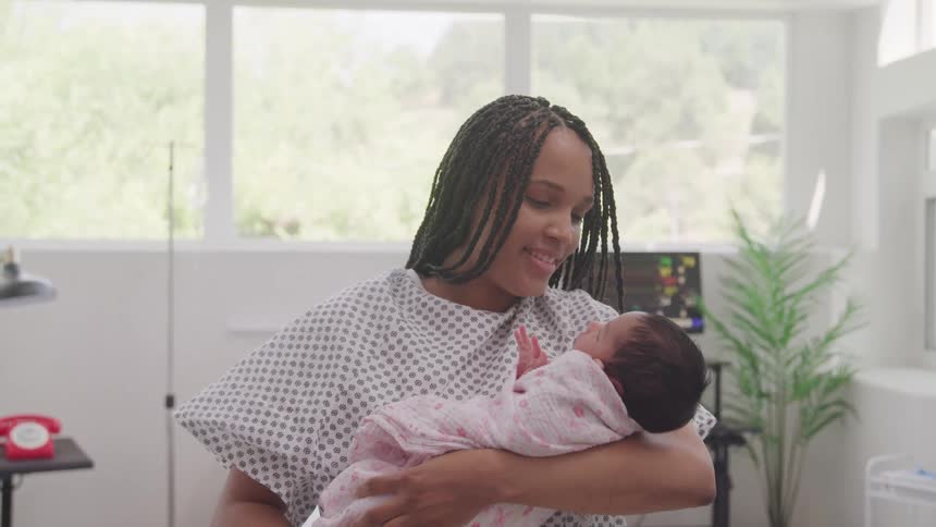 The mother smiles while cradling her baby