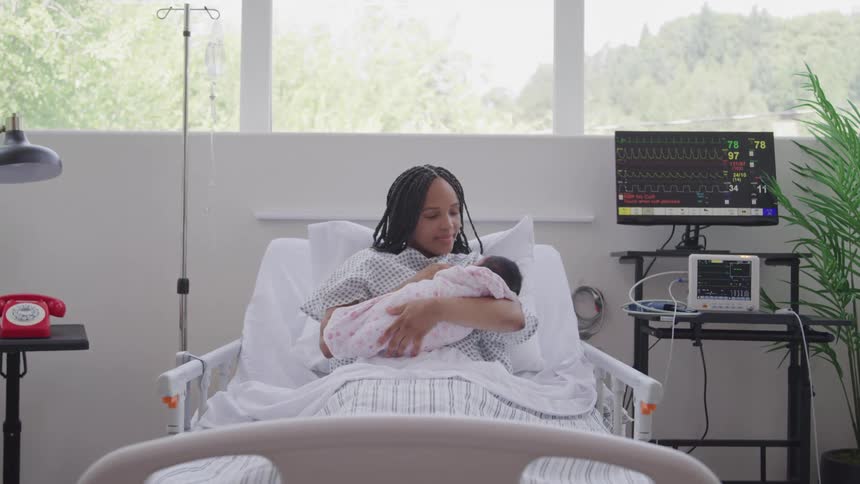 A woman cradles a newborn in a hospital bed