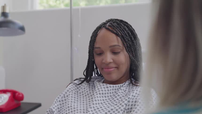 A patient smiles while listening to a nurse