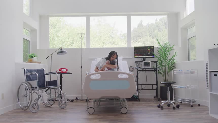A mother is holding her baby in the hospital bed