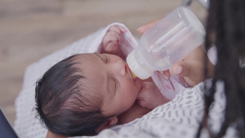 A mother feeds her newborn with a feeding bottle