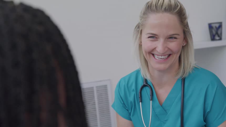 A smiling nurse attentively engages with a patient during a consultation