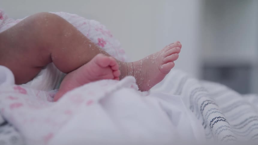 Newborn babies feet exposed while wrapped in a blanket
