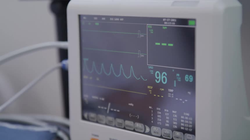 A medical monitor displays vital signs including heart rate and blood pressure