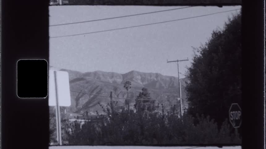 Blackandwhite archival shot of a quiet suburban street with a stop sign and hills