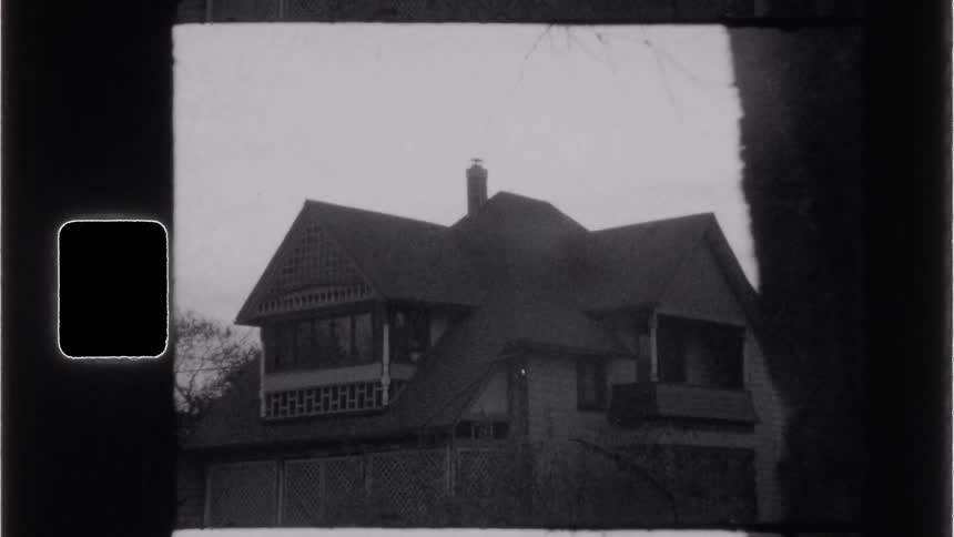 A black and white film frame shows an old house captured in vintage style