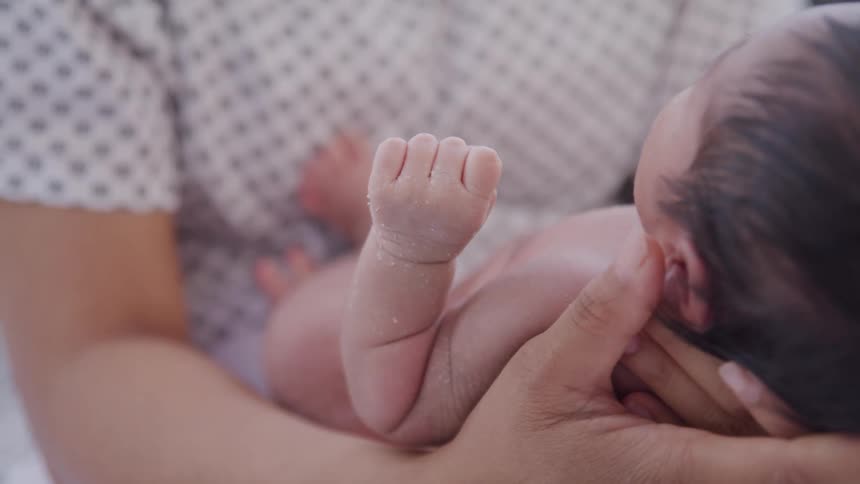 Close up of a baby carried by his mother while sitting in the hospital during daytime