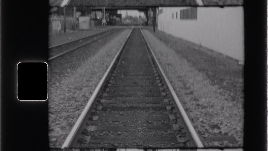 Vintage footage shows railroad tracks leading toward an overpass