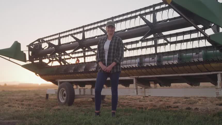 Woman in a field in front of agricultural machinery