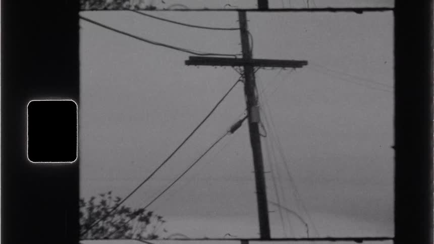 Aarchival clip shows a power line pole and trees against a quiet overcast sky