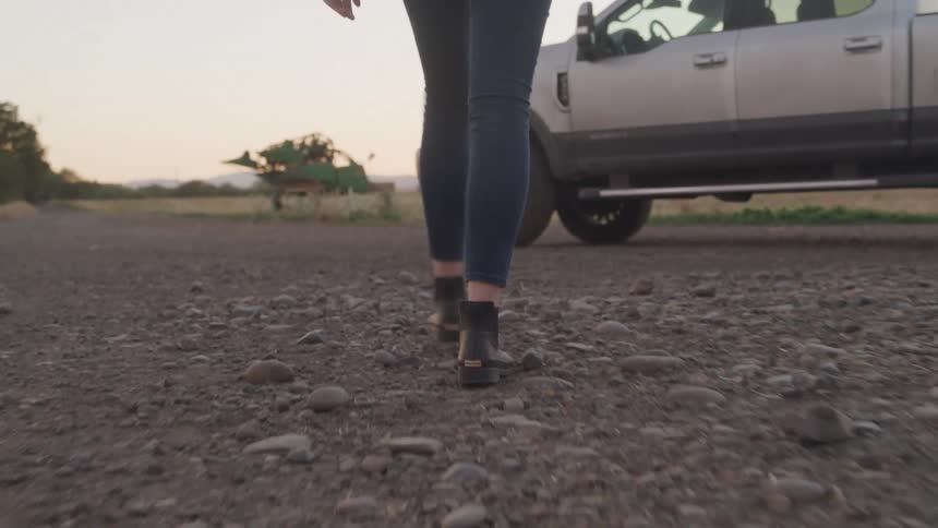 Person walks on gravel road toward a parked pickup truck