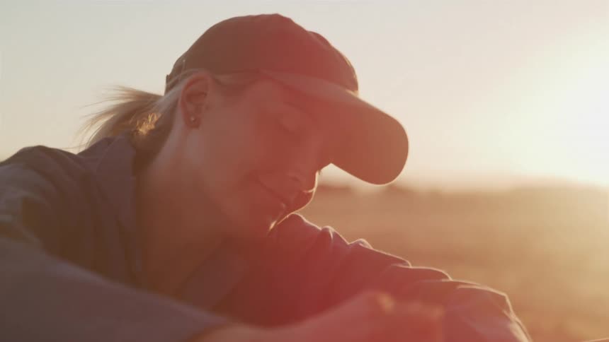 A female mechanic working on an engine in a field at sunset