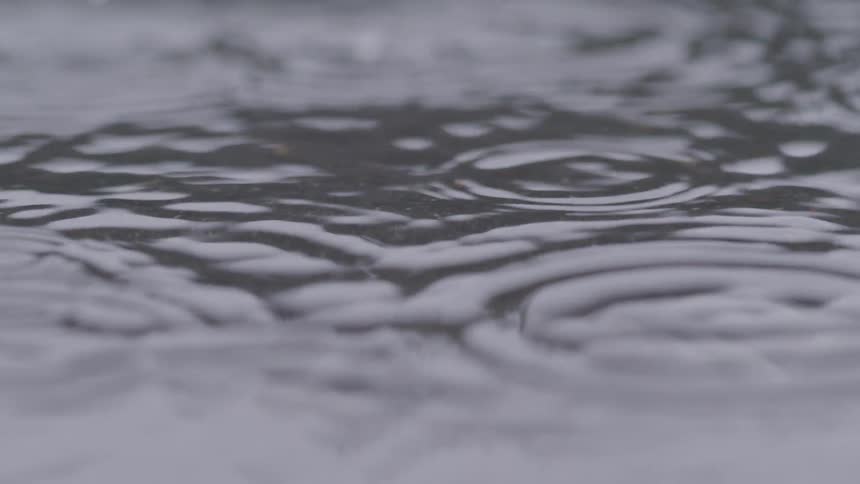 Raindrops create ripples and small splashes on the water
