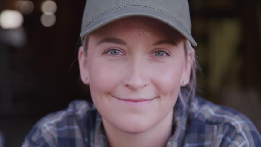 A young woman in a cap smiles warmly at the camera