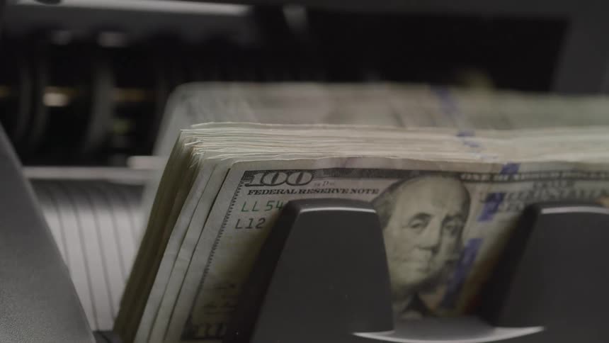 Close up of an electronic currency counter counting dollar notes