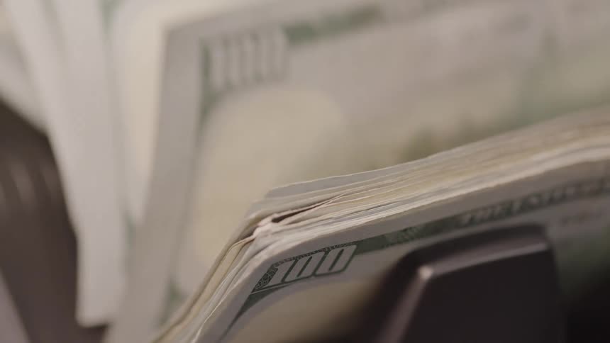 Close up of currency bills counted with an electronic bill counter