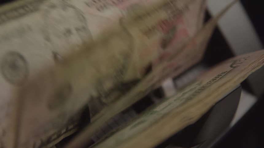 Close up of a bundle of paper currency counted by an electronic money counter