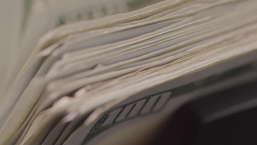 Close up of a counting machine counting one hundred dollar bills
