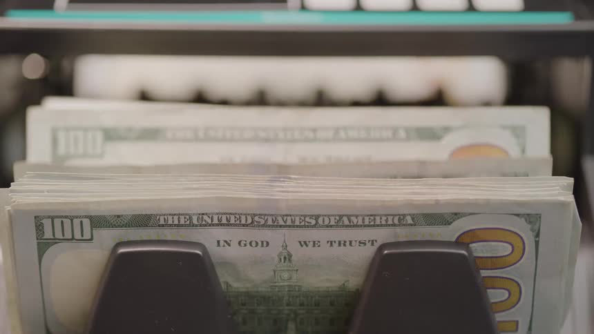 Hundred dollar bills are stacked together via machine
