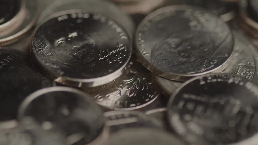 A circling view of a pile of assorted dimes of various years showing the white house and heads of founding presidents