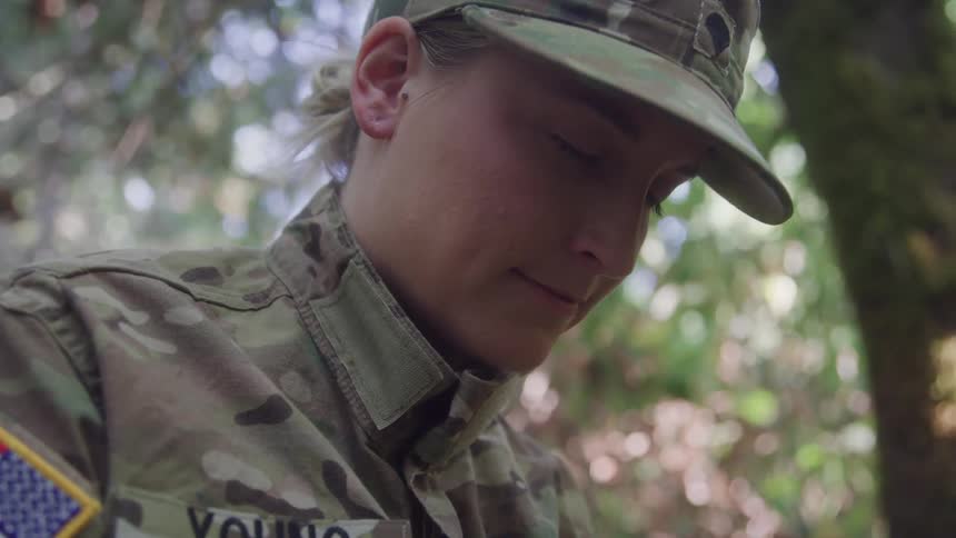 The soldier is looking down with her eyes closed