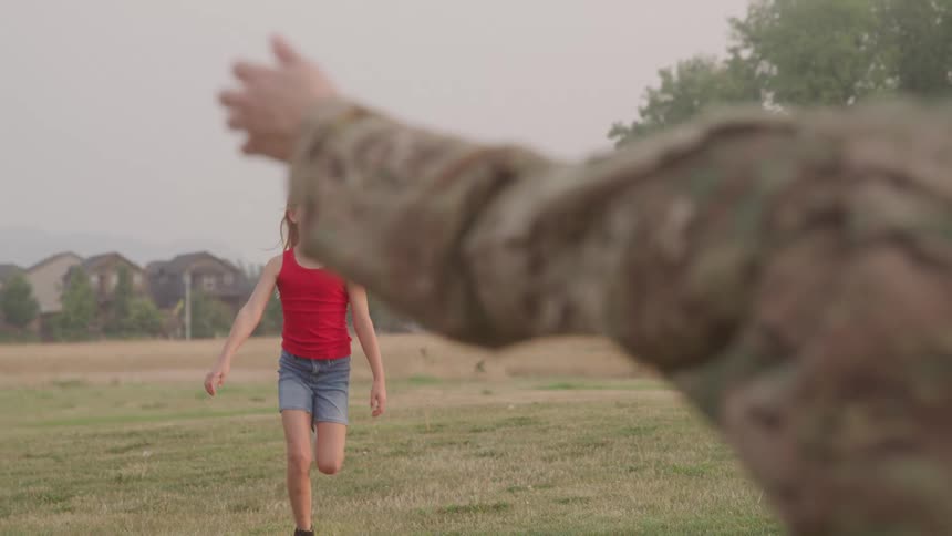 Little girl running across a field towards a woman in a military uniform