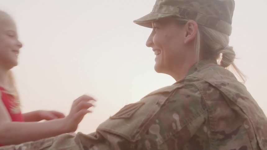 Mother in military uniform hugging her little daughter