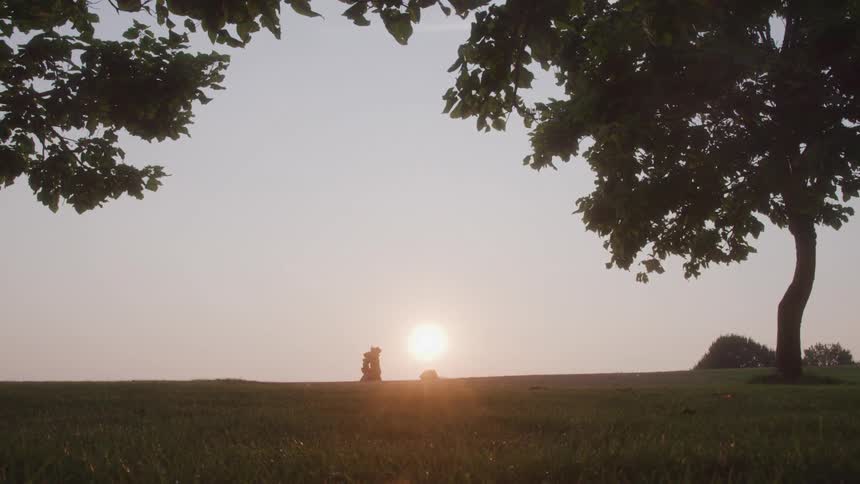 Adult person and a child running in a field and hugging each other with the sun on the horizon