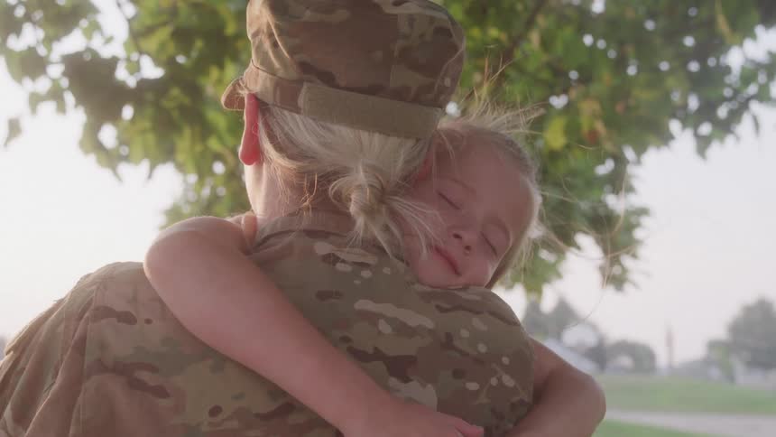 Mother in military clothing hugging a child