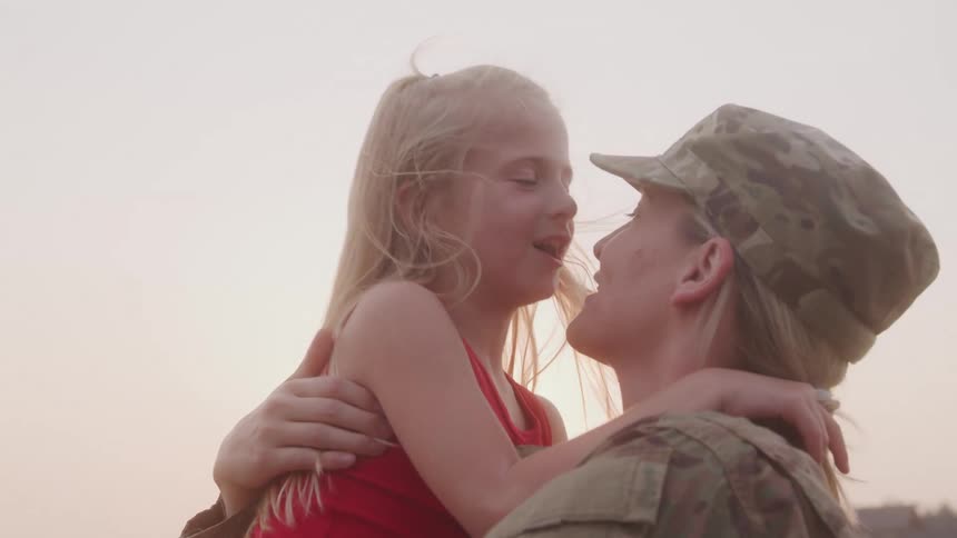 A soldier holds and kisses her daughter